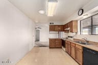 kitchen featuring brown cabinetry, light countertops, dishwasher, and a sink