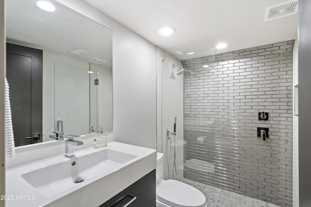 bathroom featuring toilet, a tile shower, and vanity