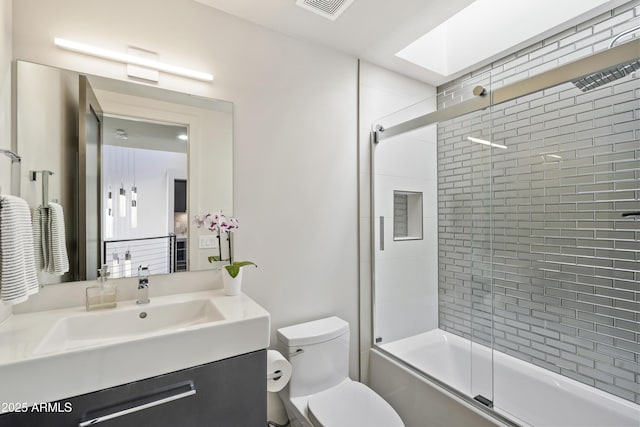 full bathroom featuring toilet, vanity, bath / shower combo with glass door, and a skylight