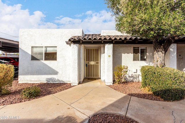 view of exterior entry featuring a tile roof and stucco siding