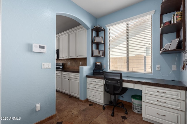 13629 W San Miguel Ave, Litchfield Park, AZ 85340 - office space with built in desk, arched walkways, baseboards, and stone finish flooring