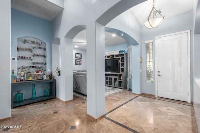 13629 W San Miguel Ave, Litchfield Park, AZ 85340 - entrance foyer featuring vaulted ceiling, arched walkways, baseboards, a dry bar, and inlaid floor details