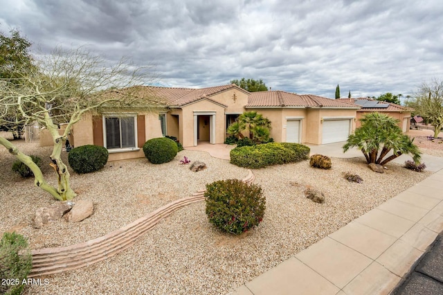 view of front facade featuring driveway, an attached garage, a tile roof, and stucco siding