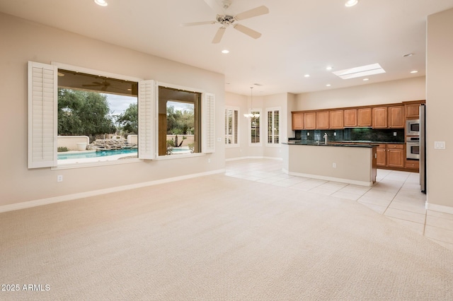 kitchen featuring light carpet, open floor plan, appliances with stainless steel finishes, decorative backsplash, and dark countertops