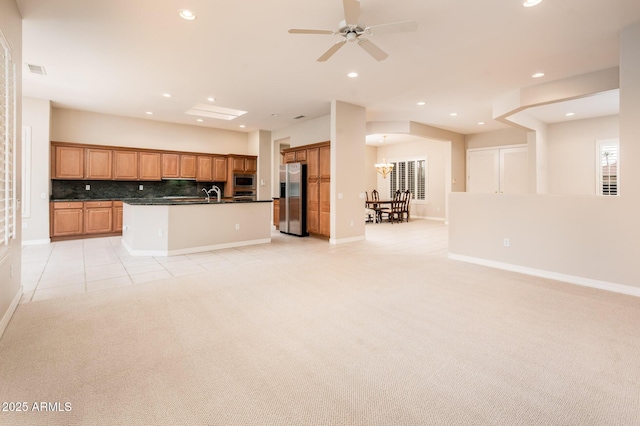 kitchen with stainless steel appliances, dark countertops, open floor plan, light carpet, and a sink