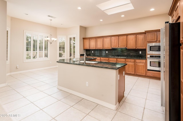 kitchen with brown cabinets, stainless steel appliances, backsplash, and light tile patterned flooring