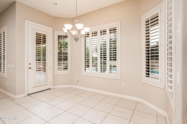 unfurnished dining area with tile patterned flooring, baseboards, and a chandelier