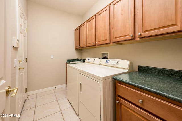 laundry area with cabinet space, light tile patterned floors, baseboards, and washer and clothes dryer