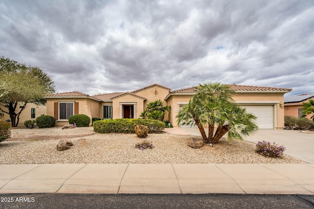 mediterranean / spanish-style home featuring concrete driveway, an attached garage, a tile roof, and stucco siding