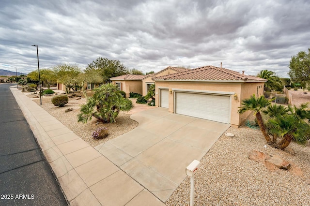 mediterranean / spanish-style home with a garage, driveway, a tile roof, and stucco siding