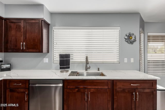 kitchen with a sink, dark brown cabinets, and light stone counters