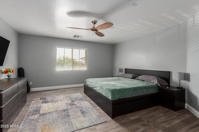 bedroom featuring baseboards, visible vents, a ceiling fan, and wood finished floors