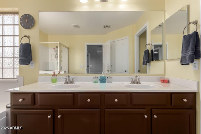 bathroom featuring a stall shower, double vanity, visible vents, and a sink