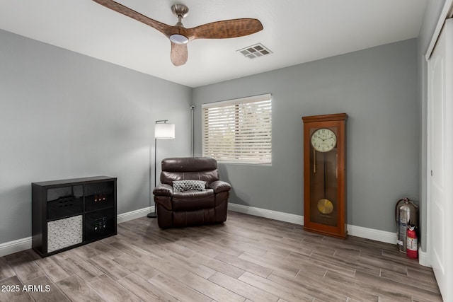 living area with baseboards, ceiling fan, visible vents, and wood finished floors