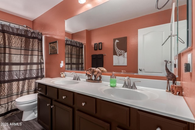 bathroom with toilet, a sink, double vanity, and wood finished floors
