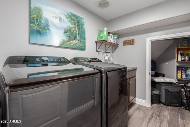 laundry area featuring washing machine and dryer, wood finish floors, baseboards, visible vents, and cabinet space