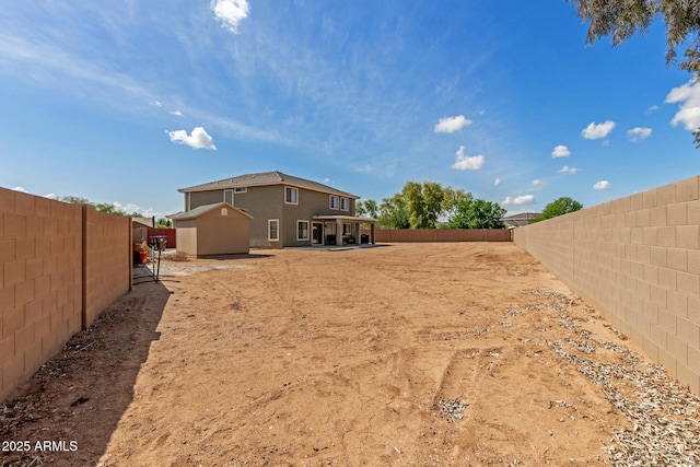 view of yard with a fenced backyard, an outbuilding, and a shed