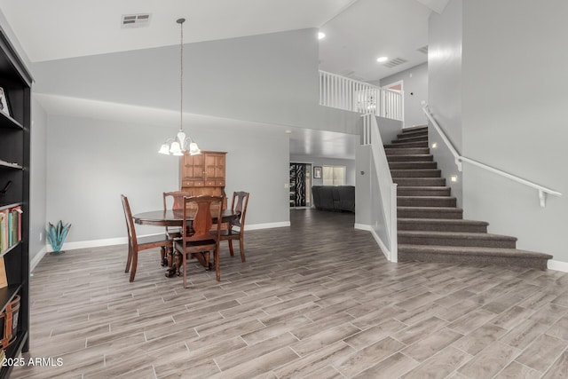dining room featuring visible vents, wood finished floors, a chandelier, and stairway