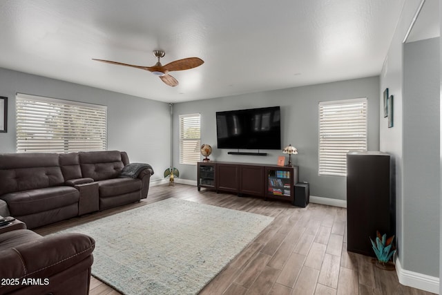 living area with baseboards, wood finished floors, and a ceiling fan