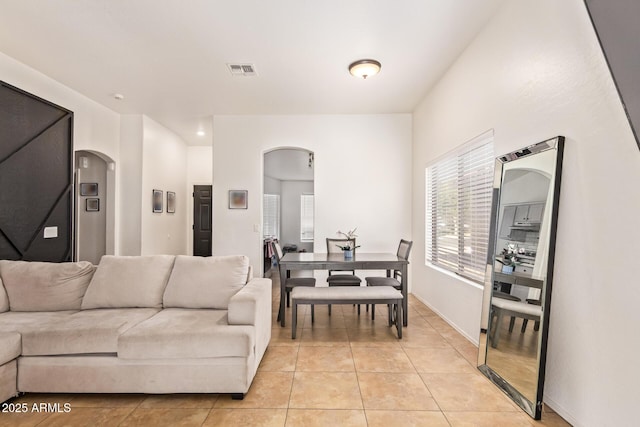 7310 N 68th Ln, Glendale, AZ 85303 - living room featuring arched walkways, light tile patterned floors, and plenty of natural light