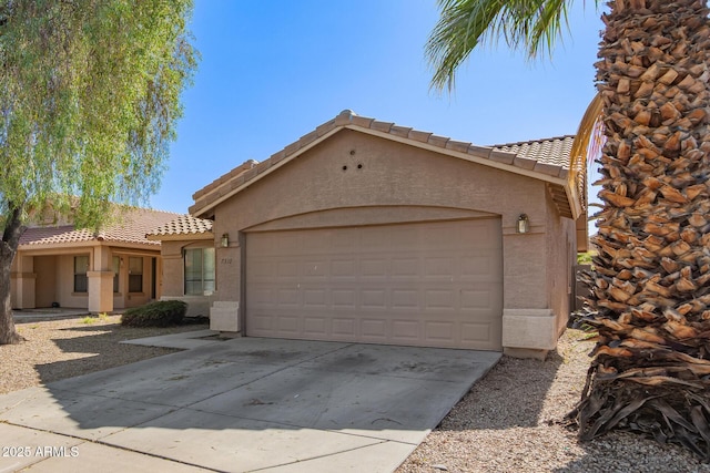 7310 N 68th Ln, Glendale, AZ 85303 - mediterranean / spanish-style house featuring stucco siding, a tile roof, an attached garage, and concrete driveway