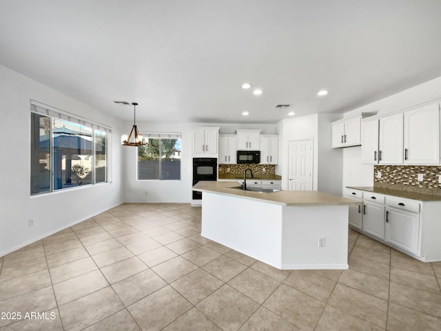 kitchen with pendant lighting, light tile patterned floors, black appliances, and white cabinets