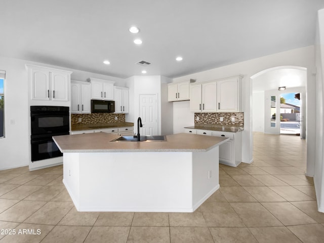 kitchen with white cabinetry, sink, a center island with sink, and black appliances