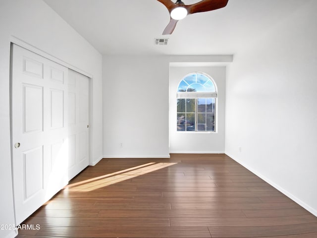 unfurnished bedroom with ceiling fan, dark hardwood / wood-style flooring, and a closet