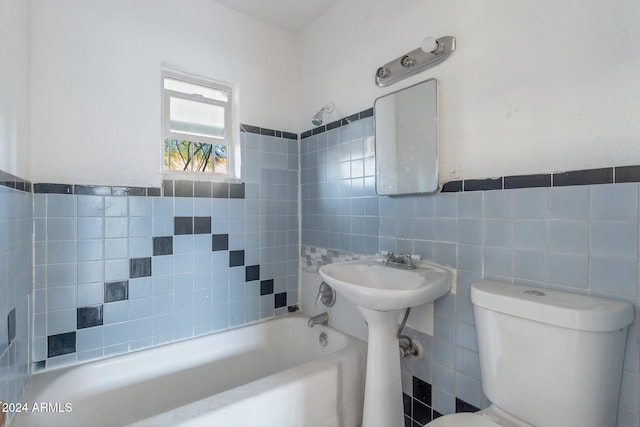 bathroom featuring tiled shower / bath, toilet, and tile walls