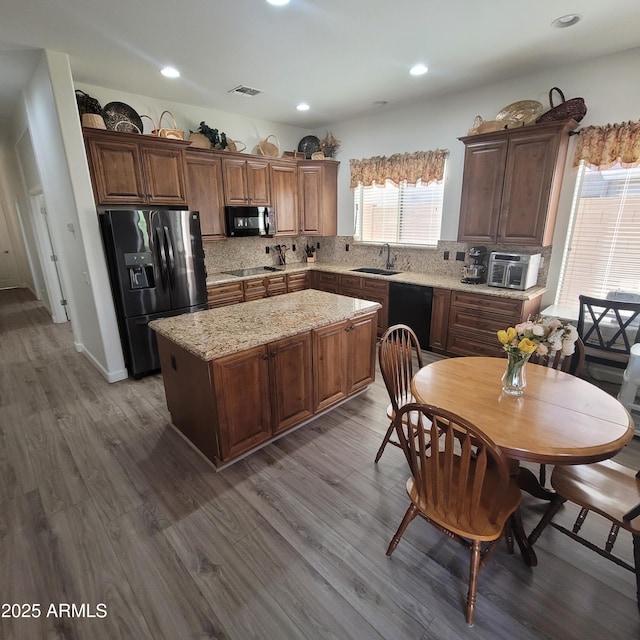 kitchen with a kitchen island, sink, dark hardwood / wood-style flooring, decorative backsplash, and black appliances