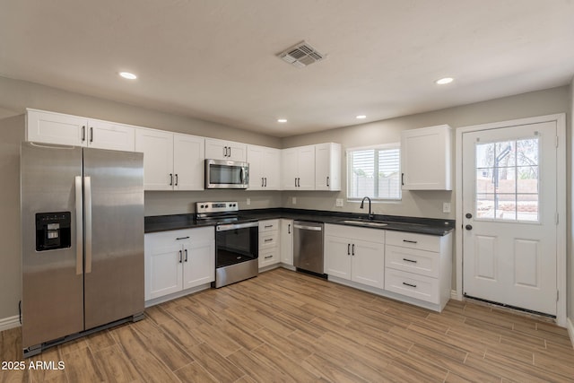 4001 E Apollo Rd, Phoenix, AZ 85042 - kitchen with appliances with stainless steel finishes, light wood-type flooring, dark countertops, white cabinets, and recessed lighting