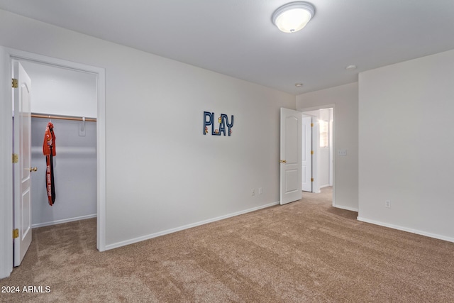unfurnished bedroom featuring a walk in closet, carpet floors, and a closet