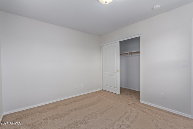 unfurnished bedroom featuring a closet and light colored carpet