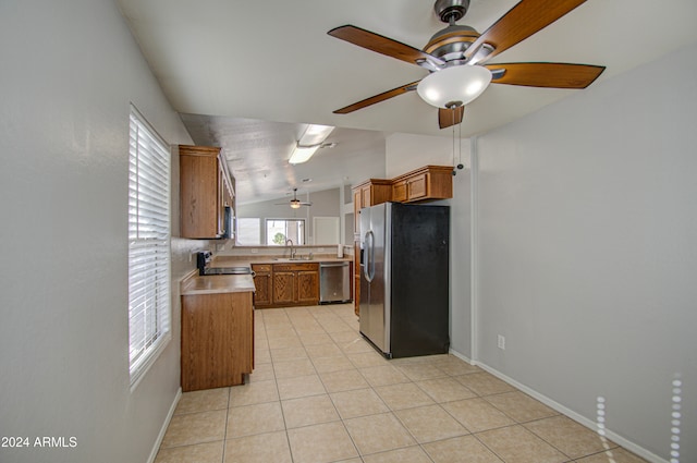 kitchen featuring ceiling fan, sink, vaulted ceiling, light tile patterned floors, and appliances with stainless steel finishes