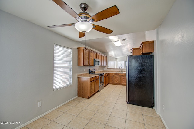 kitchen featuring ceiling fan, sink, stainless steel appliances, lofted ceiling, and light tile patterned floors