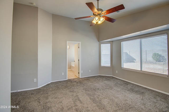 unfurnished bedroom featuring light carpet, connected bathroom, and ceiling fan