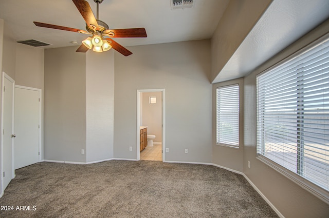 unfurnished bedroom featuring light carpet, ceiling fan, and ensuite bathroom