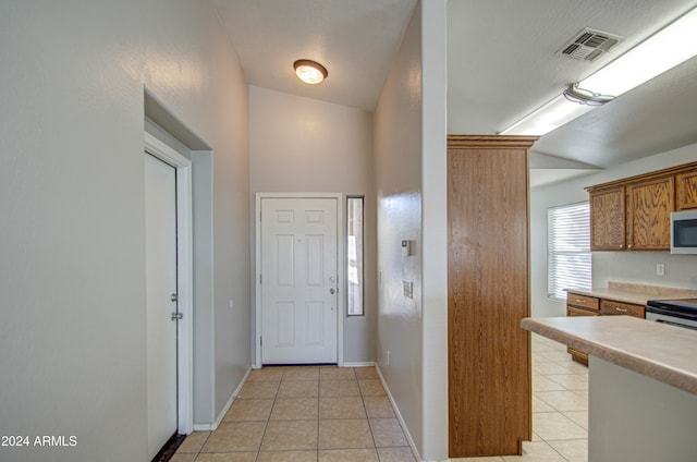 entryway with lofted ceiling and light tile patterned floors