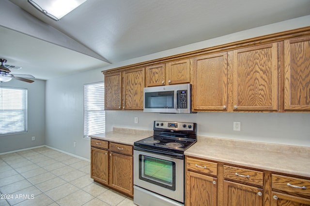 kitchen featuring ceiling fan, light tile patterned flooring, lofted ceiling, and appliances with stainless steel finishes