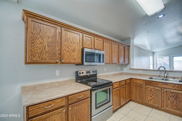 kitchen featuring sink, light tile patterned floors, stainless steel appliances, and vaulted ceiling