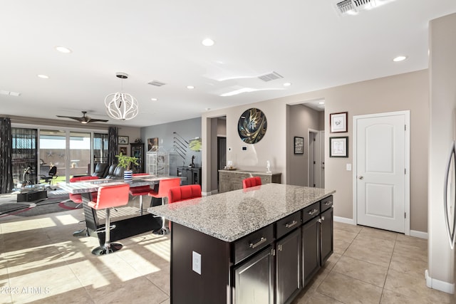 kitchen featuring light stone countertops, light tile patterned flooring, hanging light fixtures, and a center island