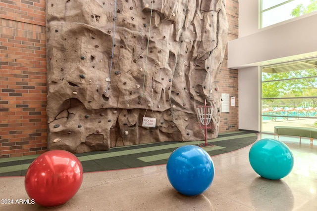 exercise room with a high ceiling and brick wall