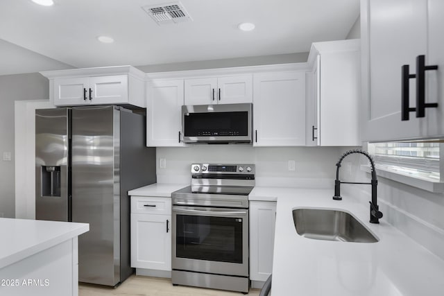 kitchen with stainless steel appliances, white cabinets, and sink