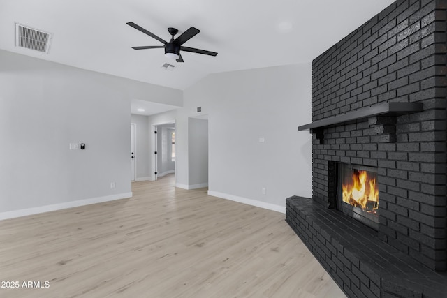 unfurnished living room with a brick fireplace, ceiling fan, vaulted ceiling, and light wood-type flooring