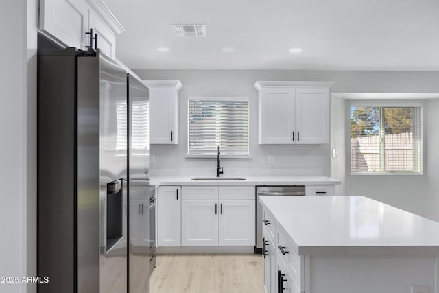 kitchen with sink, white cabinetry, light wood-type flooring, and appliances with stainless steel finishes