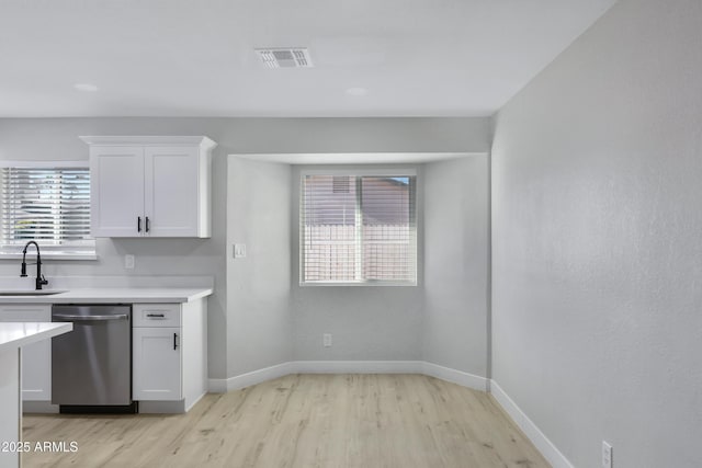 kitchen featuring white cabinets, light wood-type flooring, dishwasher, and sink