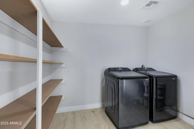 laundry room featuring light wood-type flooring and separate washer and dryer