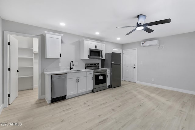 kitchen featuring stainless steel appliances, sink, white cabinets, ceiling fan, and a wall mounted air conditioner