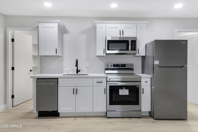 kitchen with stainless steel appliances, white cabinetry, light hardwood / wood-style flooring, and sink