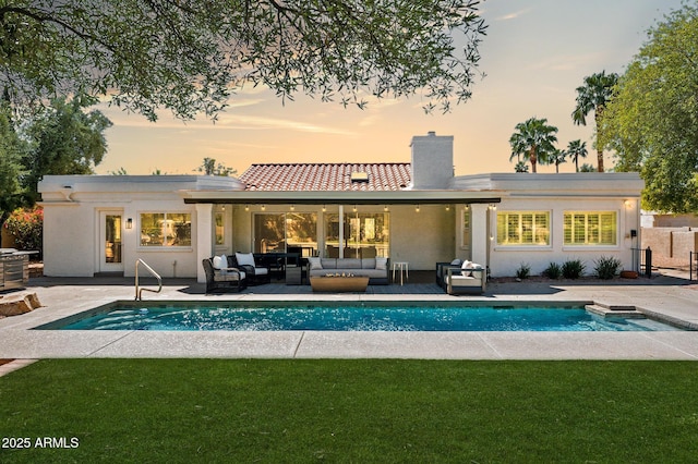 back of house featuring an outdoor living space, an outdoor pool, a patio, and a lawn